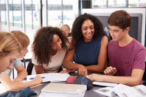 grupo de estudiantes de segundo año de secundaria sentados en una mesa de lectura