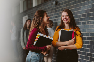 Girls carrying books and laughing in hallway