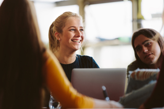 Female students using laptops and smiling