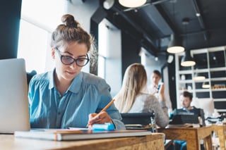 Estudiante que escribe mientras usa la computadora portátil