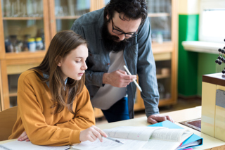 Teacher explaining lesson to female student