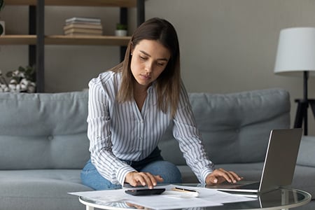 Mujer sentada en el sofá con computadora portátil en la mesa de café